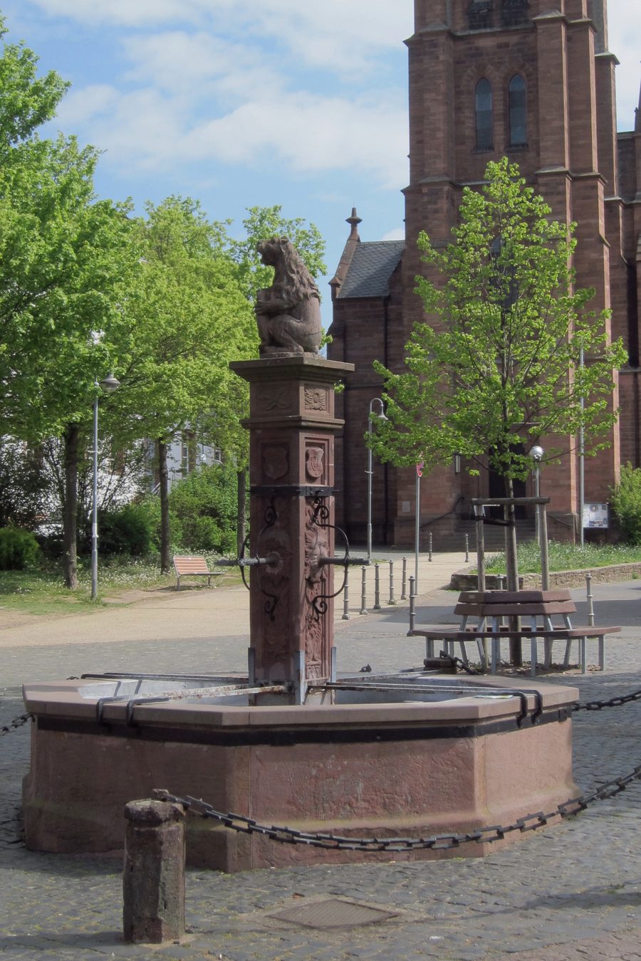 Vierröhrenbrunnen auf dem Wilhelm-Leuschner-Platz in Langen mit der Stadtkirche im Hintergrund