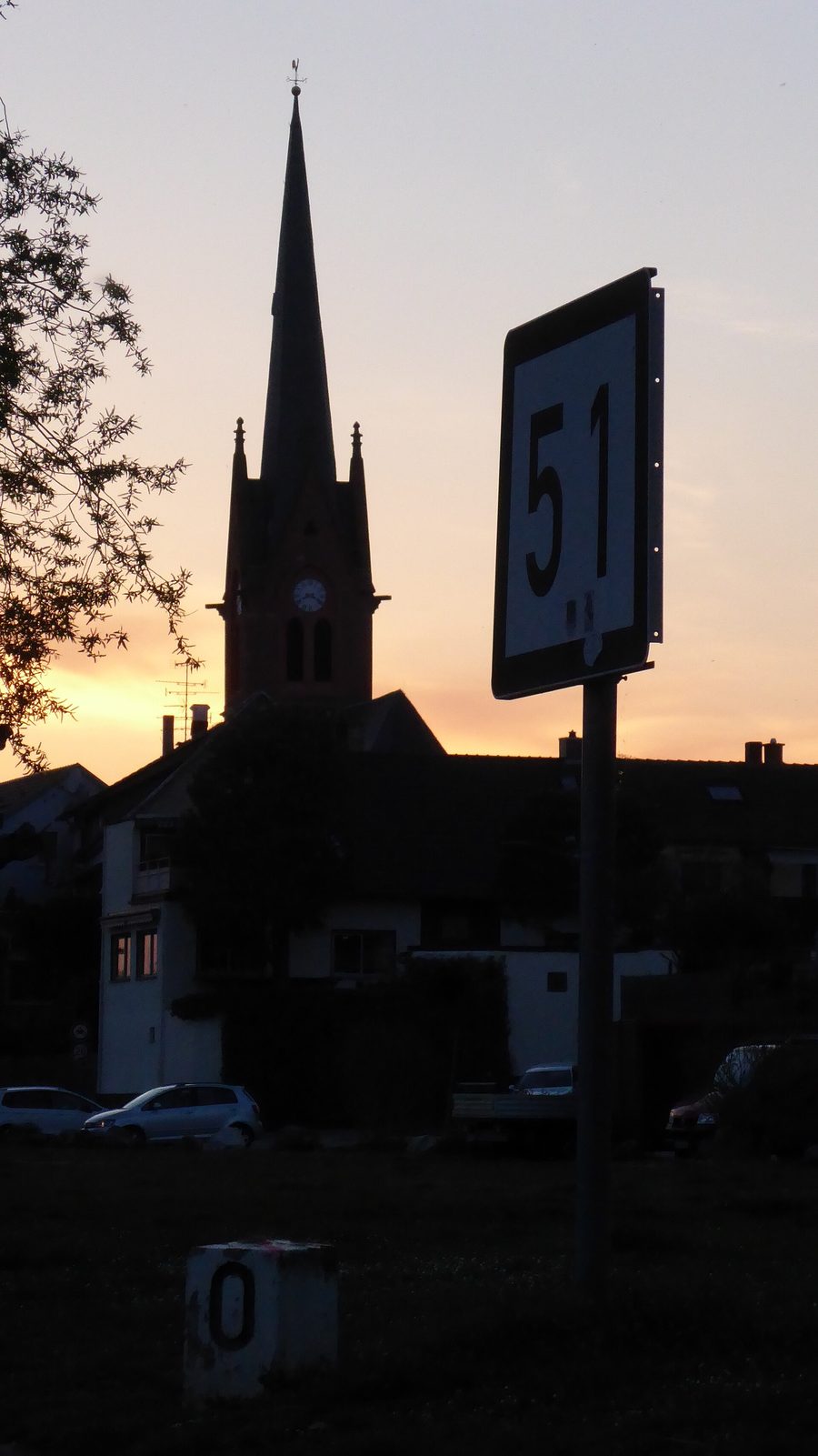 Kilometertafel 51 des Mains am Mainufer von Dörnigheim mit der alten evangelischen Kirche im Hintergrund